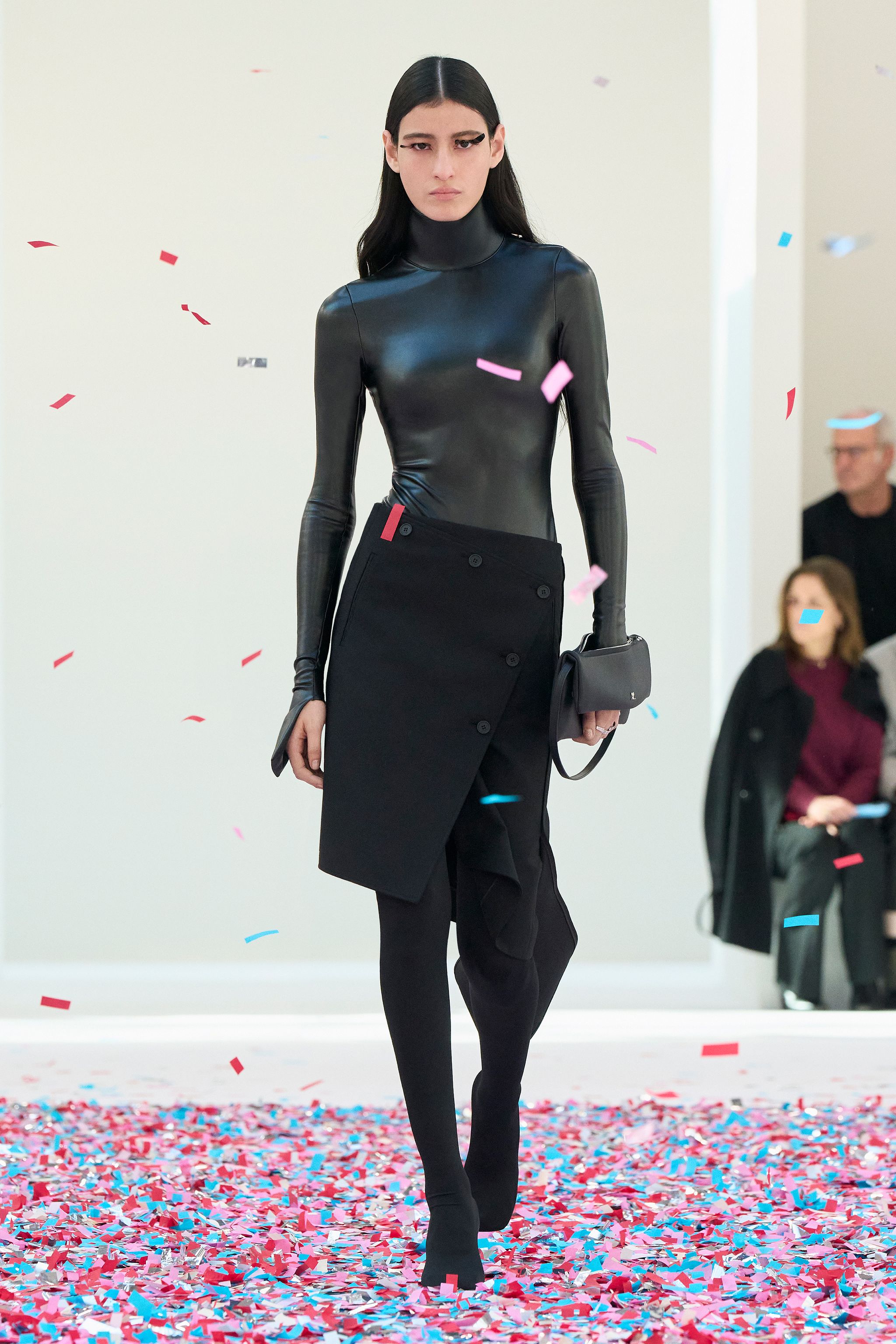 Elegant black leather top and asymmetric skirt by Courrèges on a fashion runway.