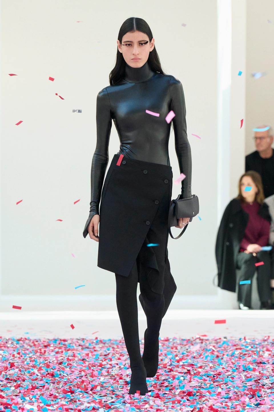 Elegant black leather top and asymmetric skirt by Courrèges on a fashion runway.