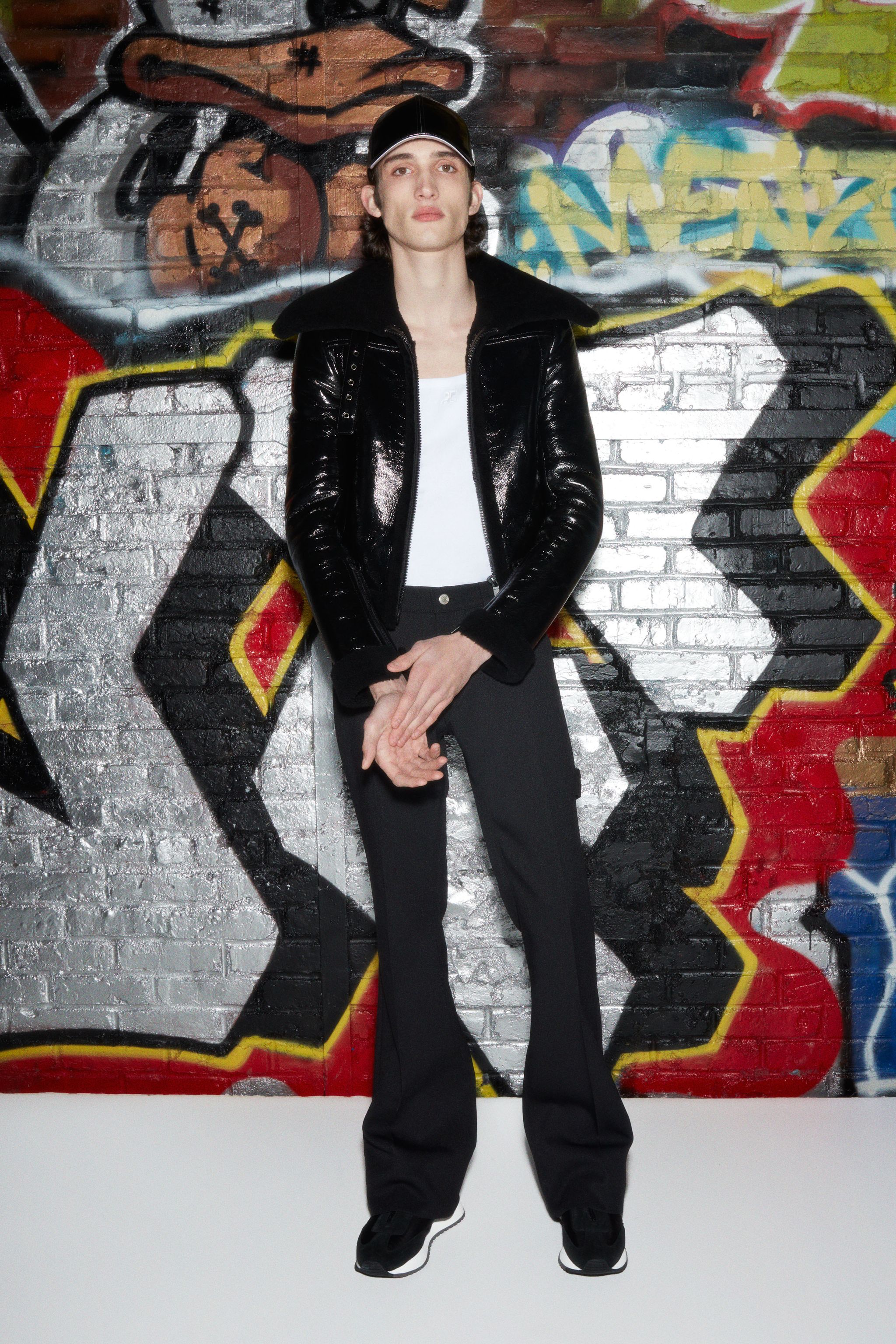 Fashion-forward model wearing shiny black leather jacket and sleek black pants at Courrèges.