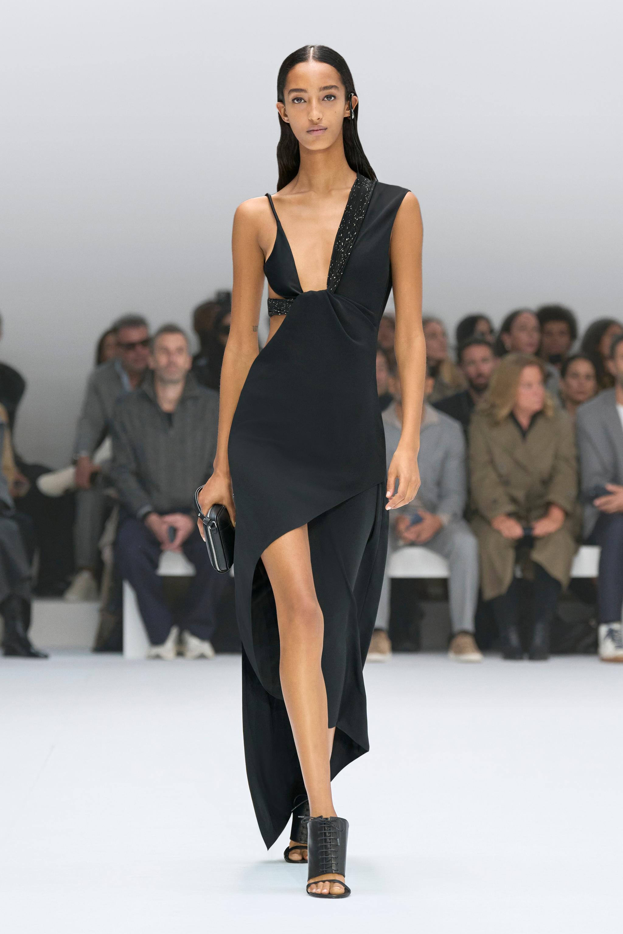 Elegant black asymmetrical dress with cutouts, showcased on a runway for Courrèges fashion.