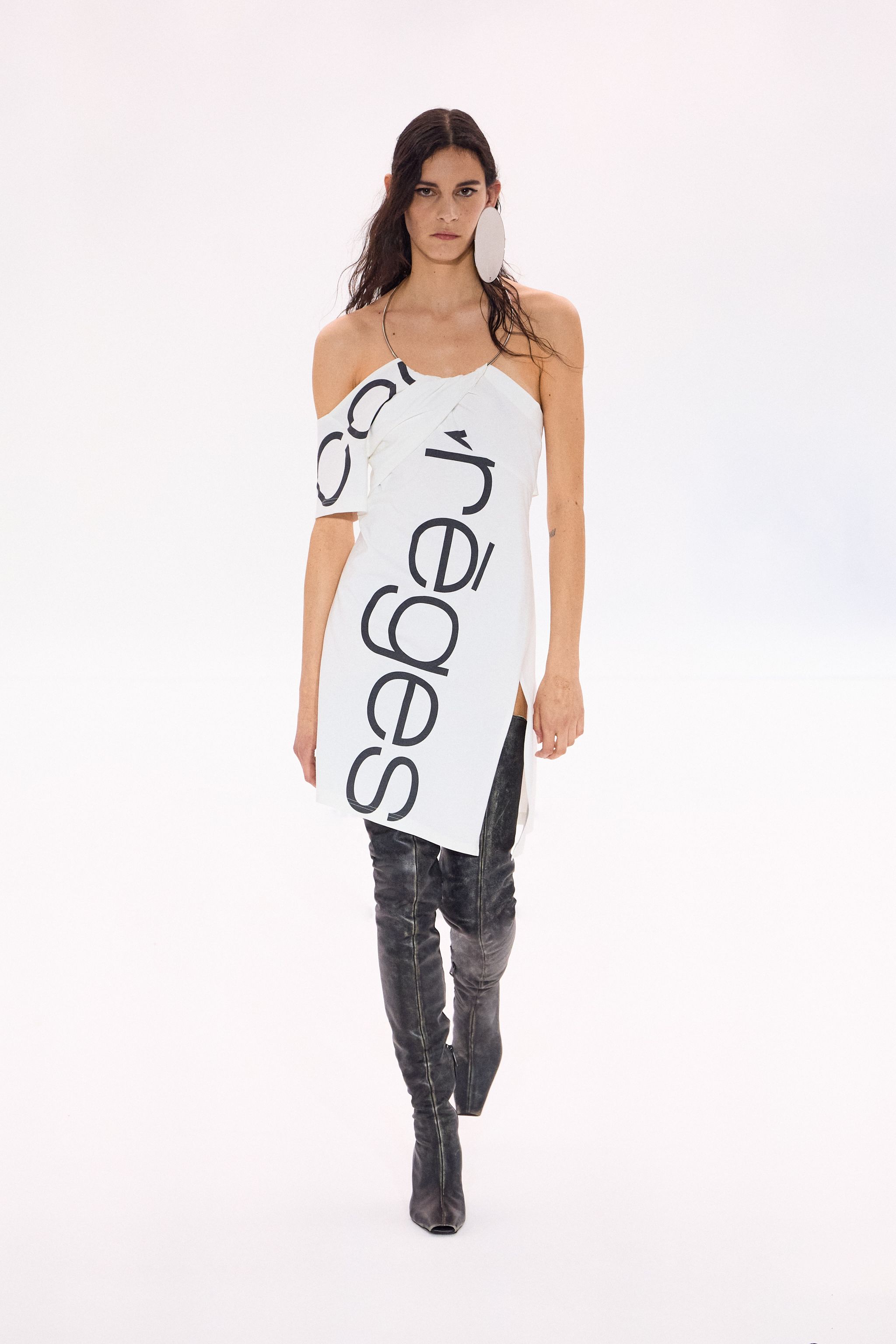 Elegant fashion model wearing a Courrèges white dress with bold black logo, modern style.