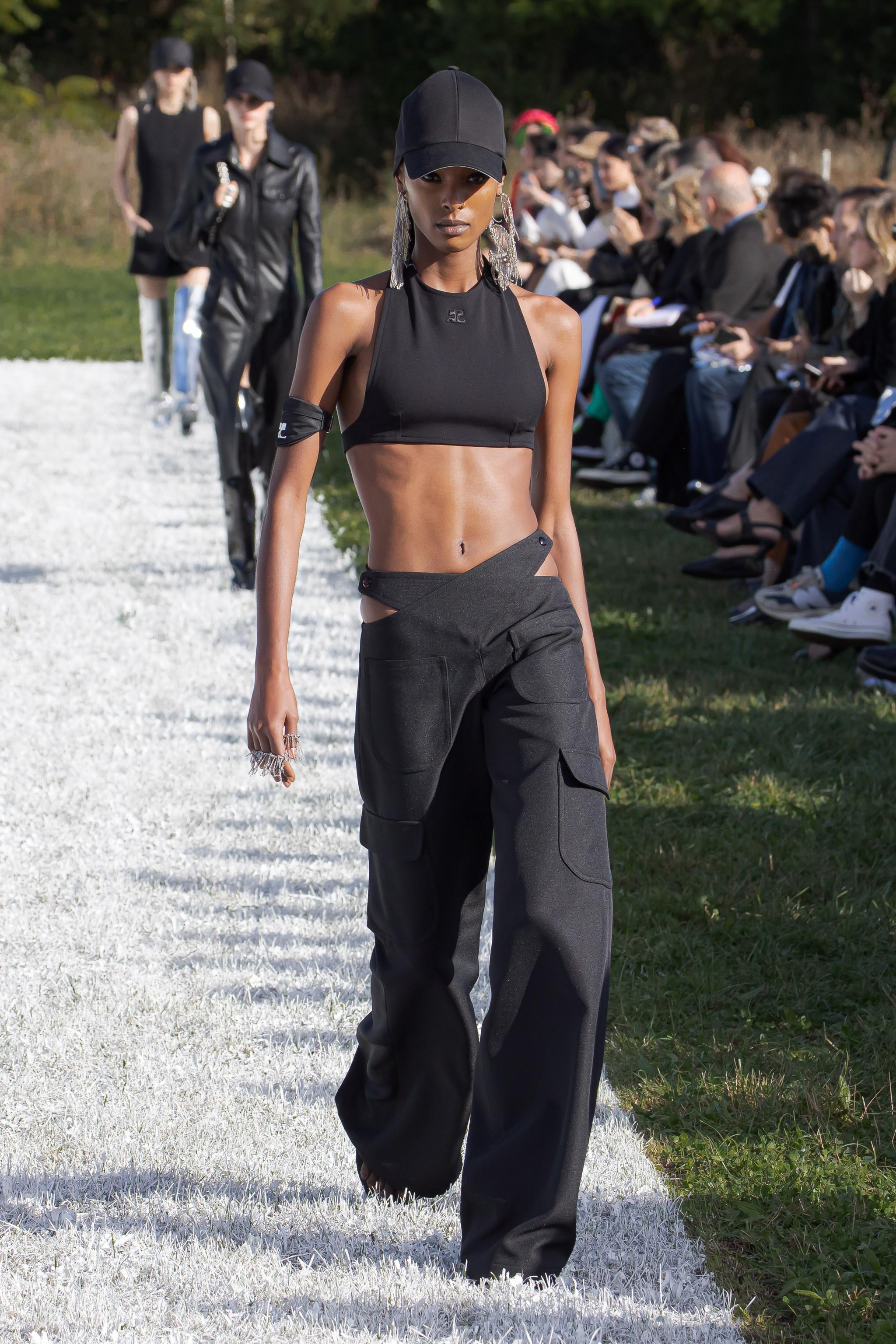 Elegant black crop top and cargo pants by Courrèges on a runway at a fashion show.