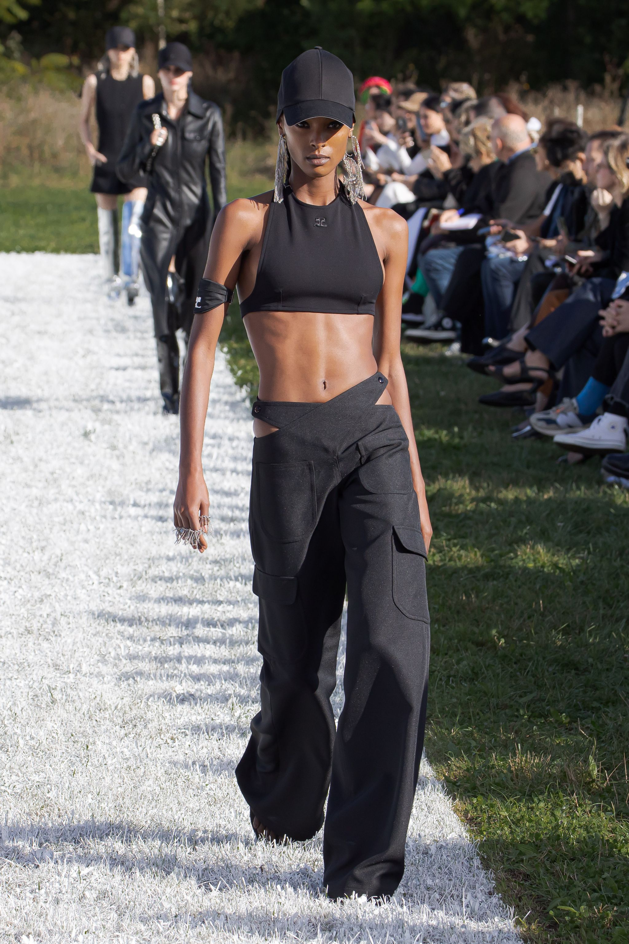 Elegant black crop top and cargo pants by Courrèges on a runway at a fashion show.