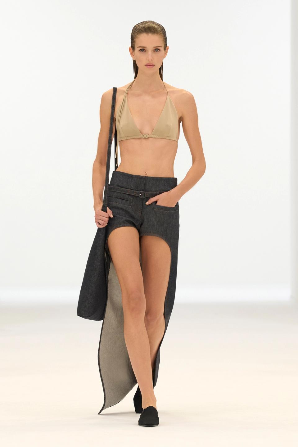 Elegant model showcases Courrèges modern fashion with a beige top and dark asymmetrical pants.