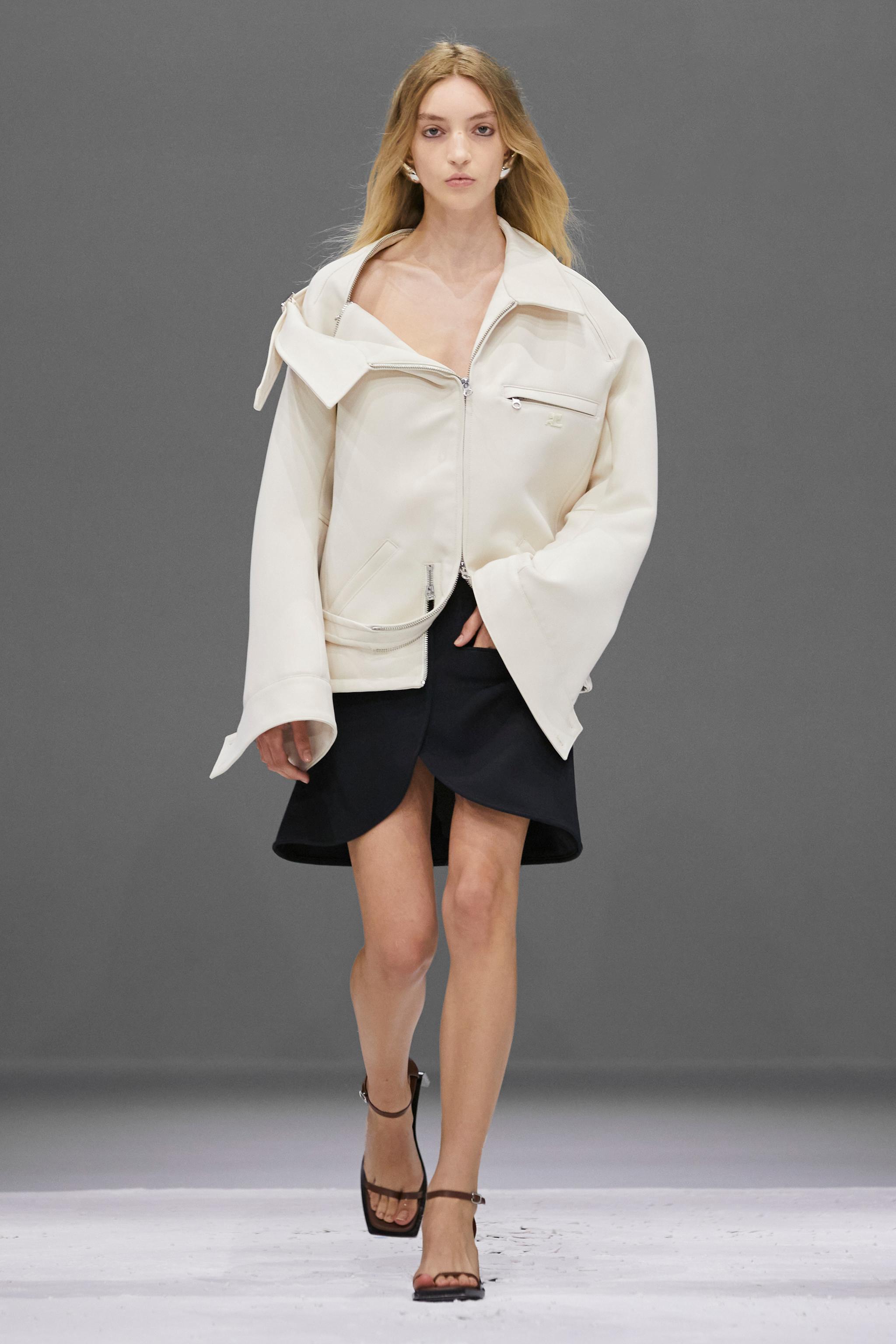 Elegant model wearing Courrèges designer jacket and stylish black skirt on fashion runway.