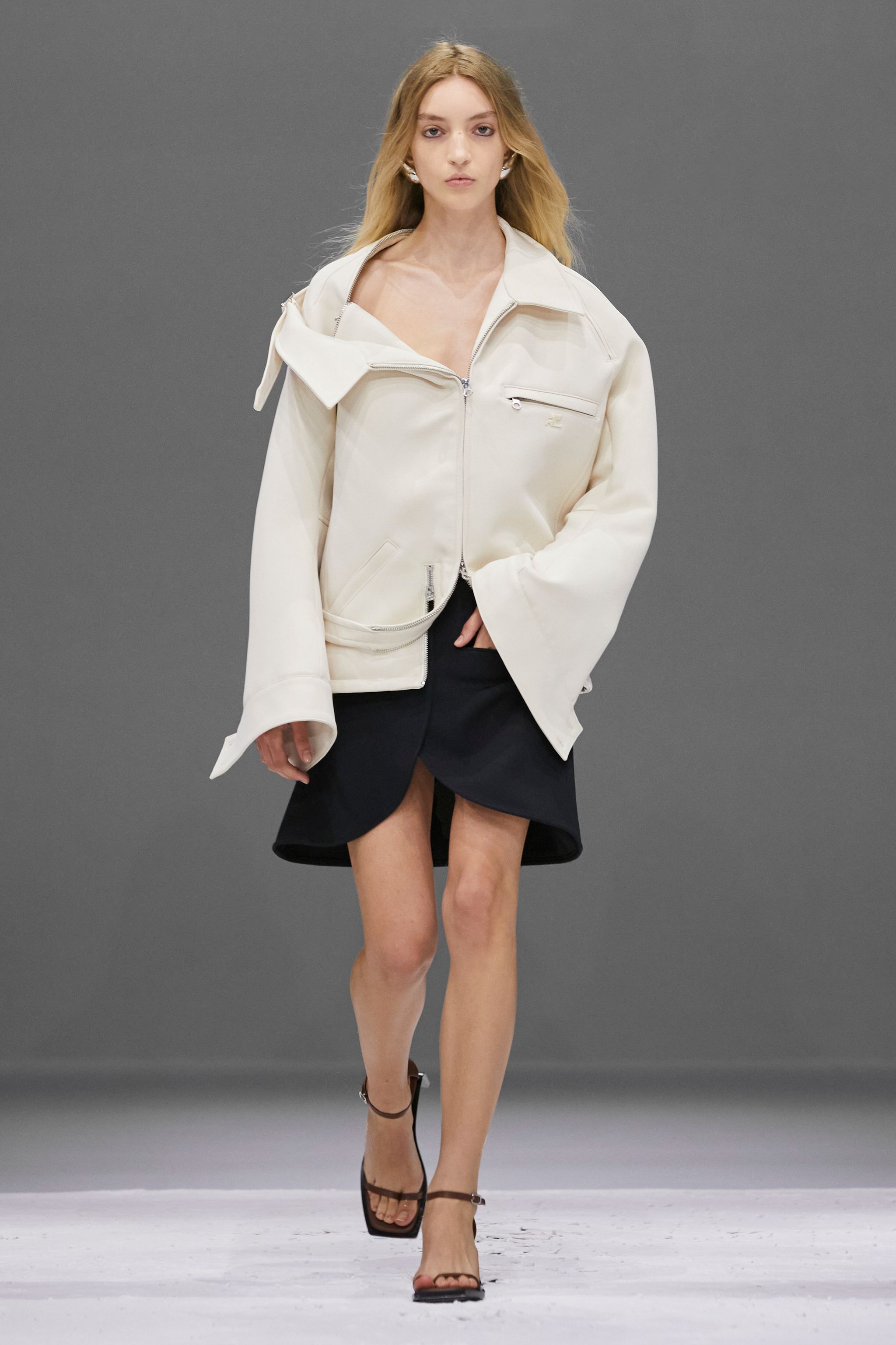 Elegant runway image of a model showcasing Courrèges fashion brand's chic white jacket.