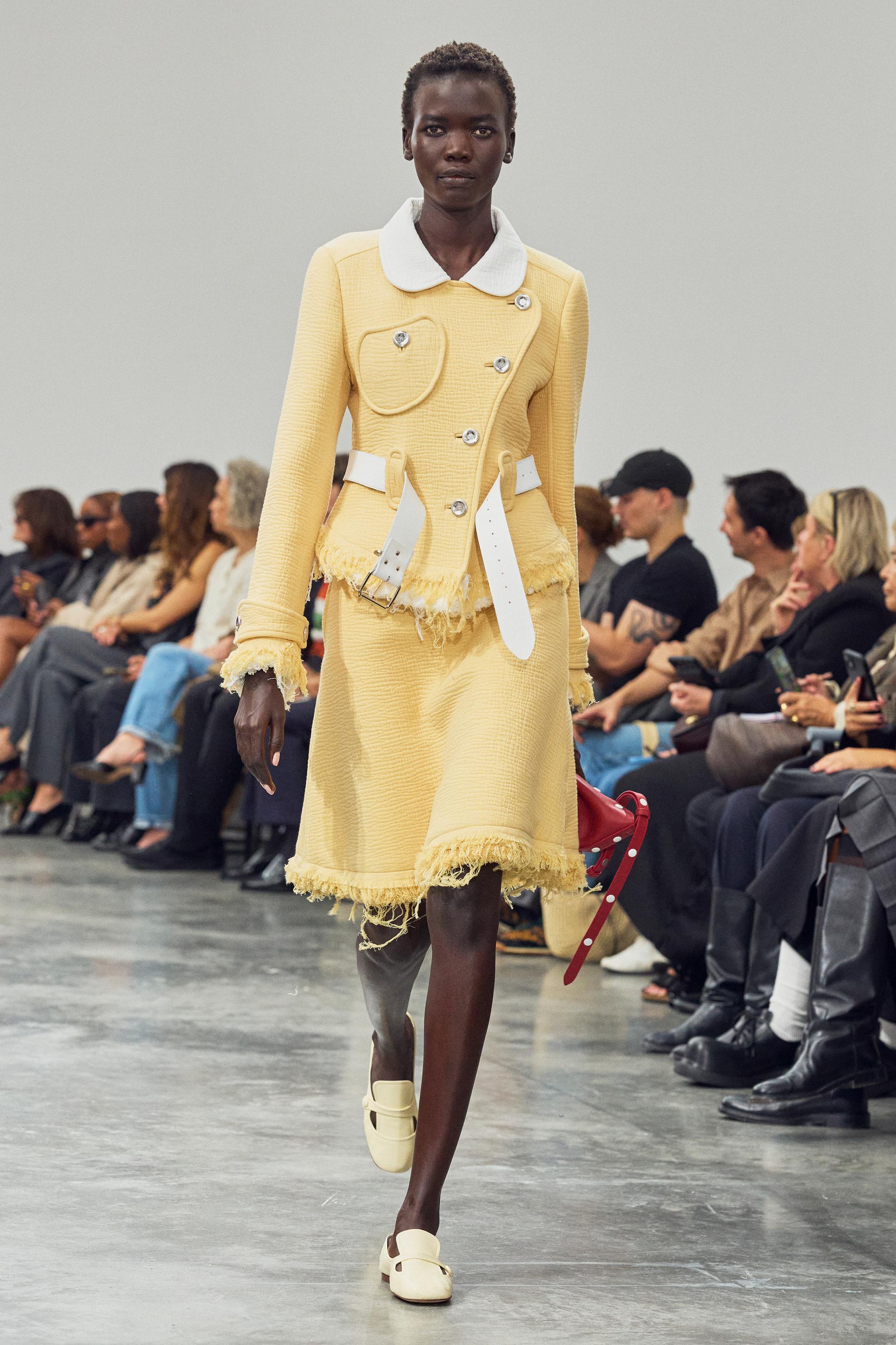 Elegant yellow Courrèges fashion runway featuring a modern fitted jacket and skirt ensemble.
