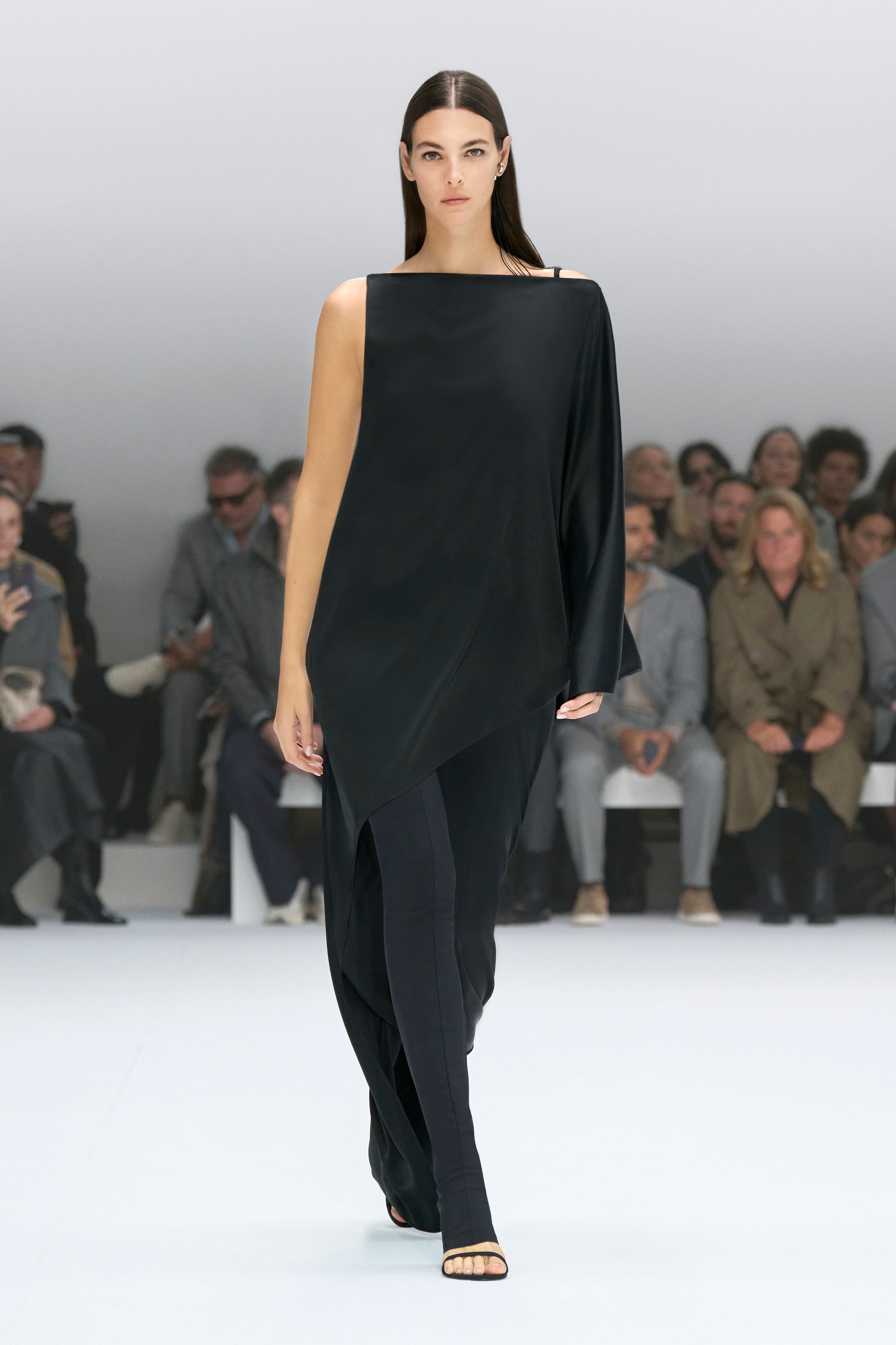 Elegant black one-shoulder dress showcased on a runway for Courrèges fashion brand.