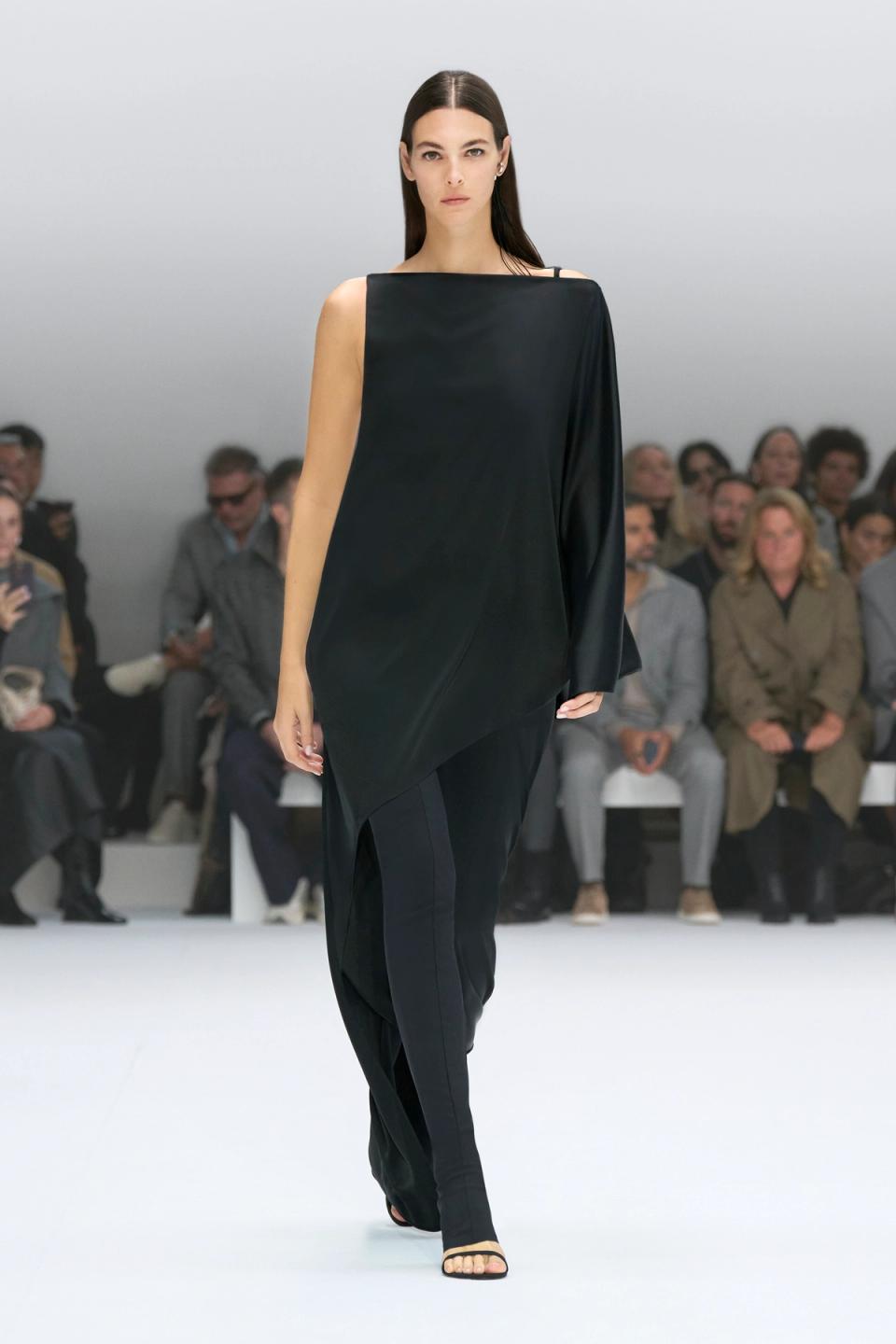 Elegant black one-shoulder dress showcased on a runway for Courrèges fashion brand.
