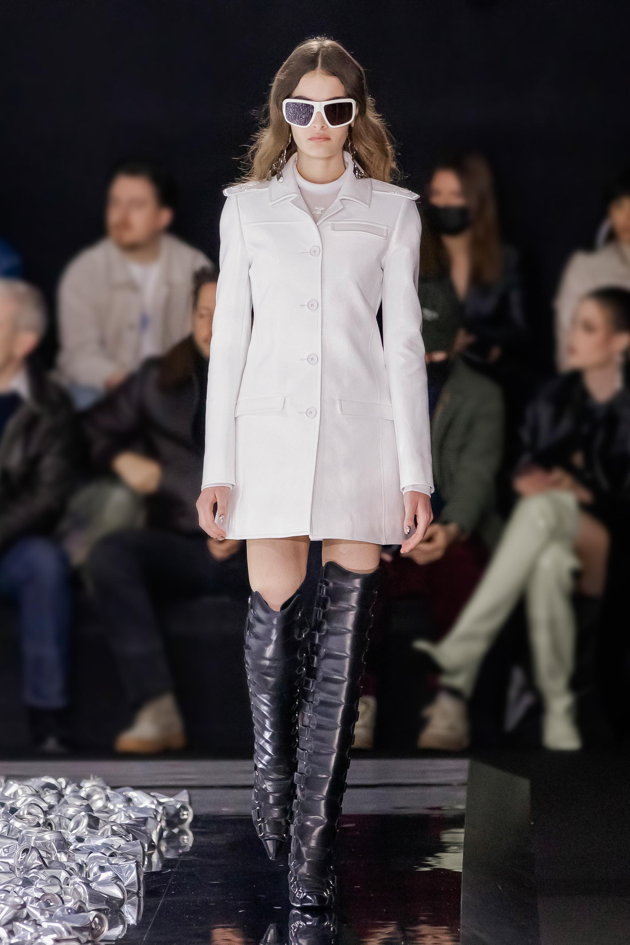 Elegant white trench coat with high black leather boots showcased for Courrèges fashion.