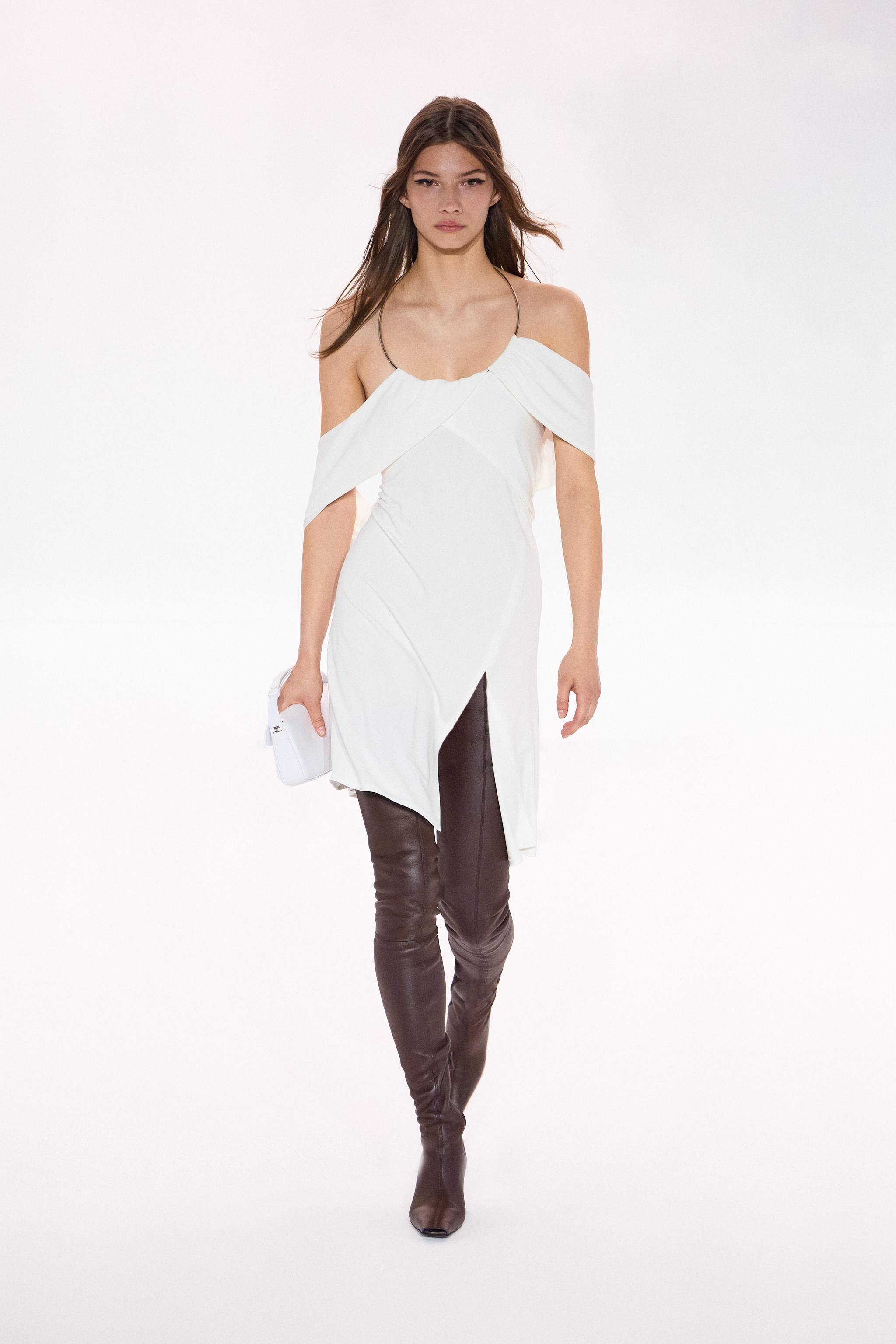 Elegant white dress with off-shoulder design and black thigh-high boots, Courrèges fashion.