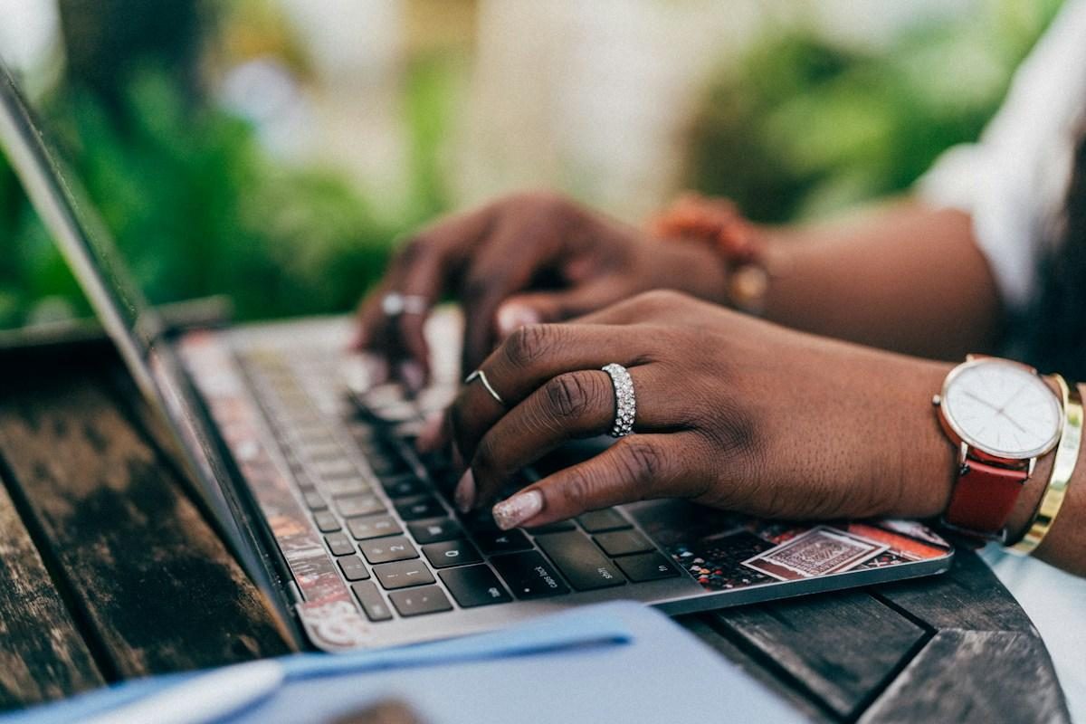 Hands typing on a laptop at an outdoor table