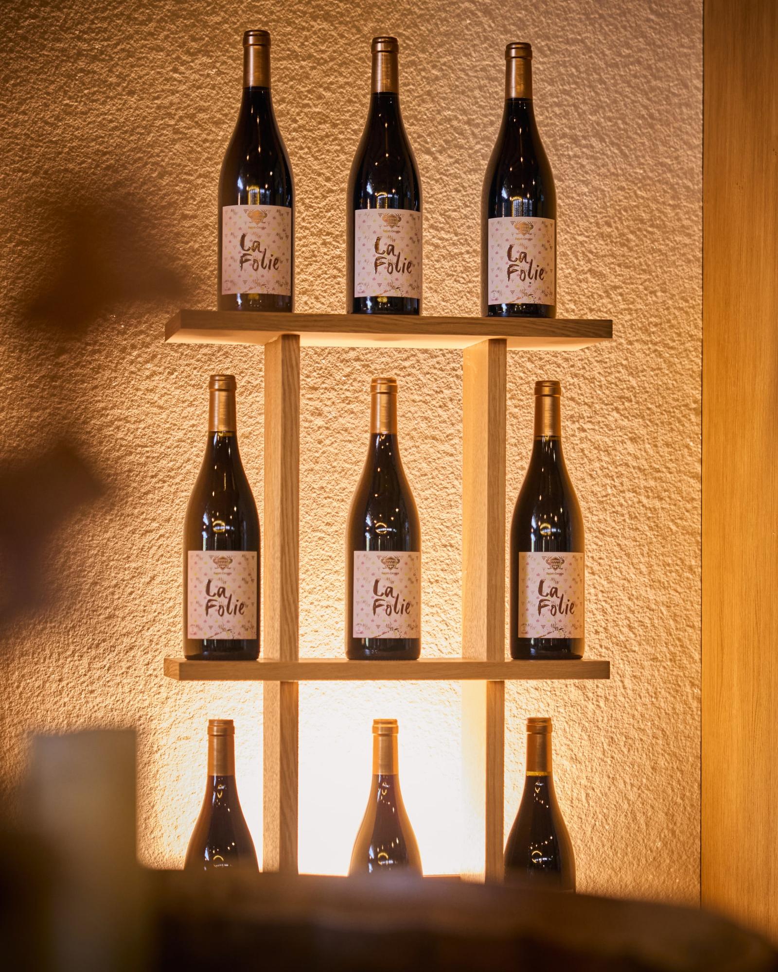 Bottles of La Folie on a lit shelf