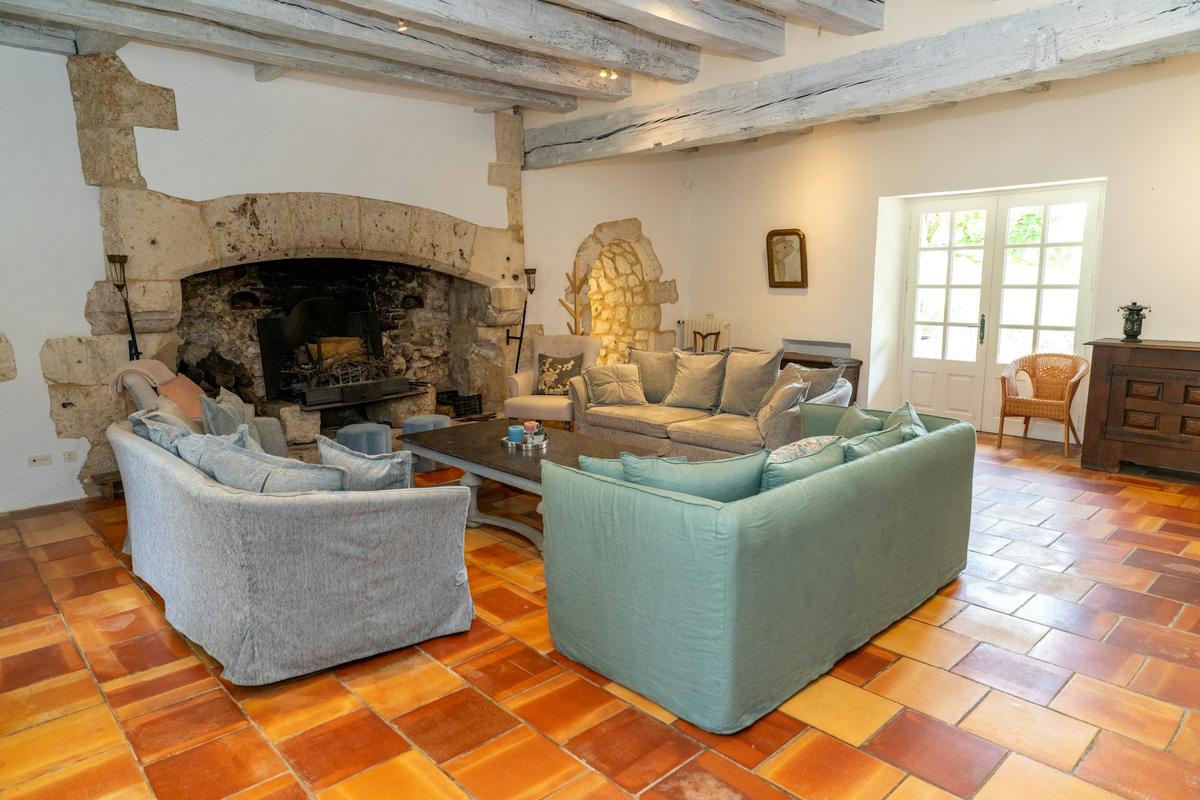 Le salon, sa cheminée en pierre et ses tomettes