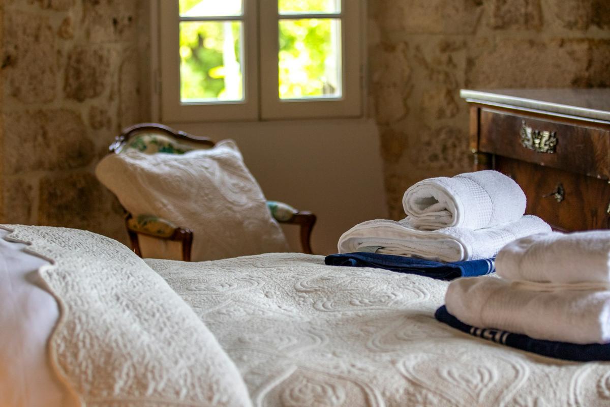 Une chambre aux murs de pierre, serviettes posées sur le lit