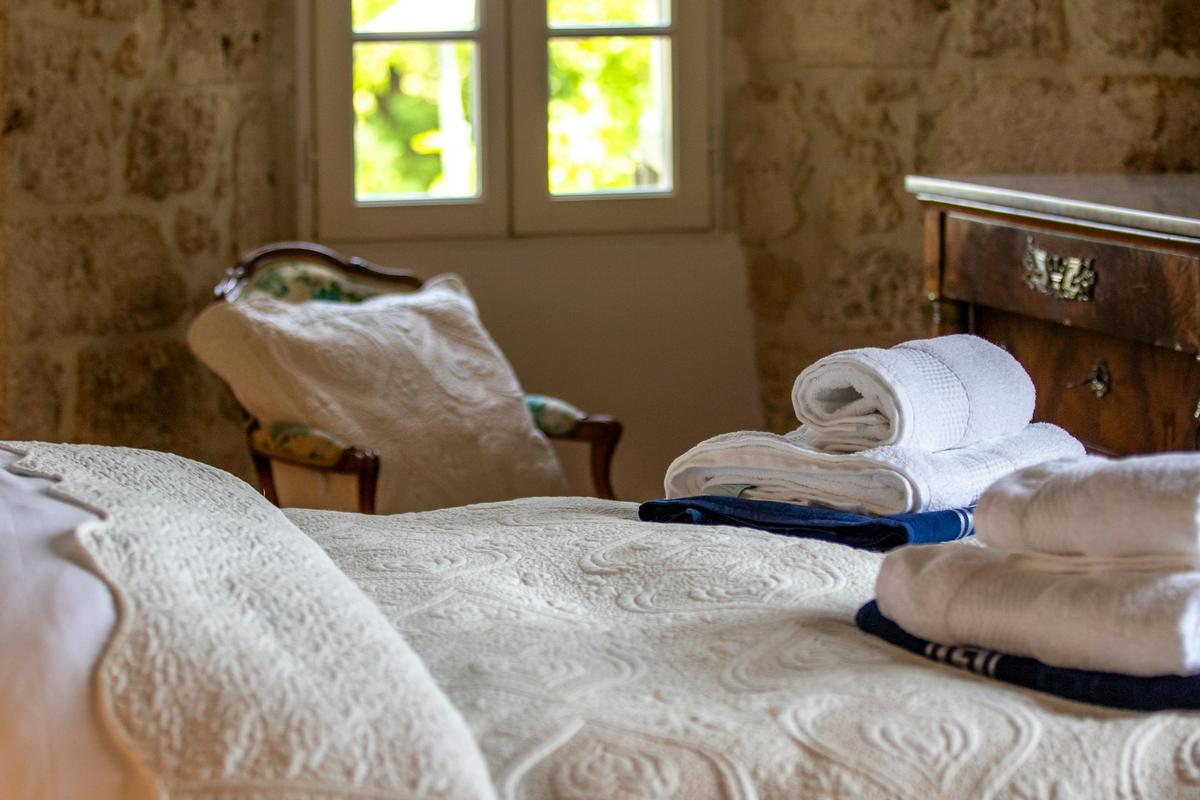 Une chambre aux murs de pierre, serviettes posées sur le lit