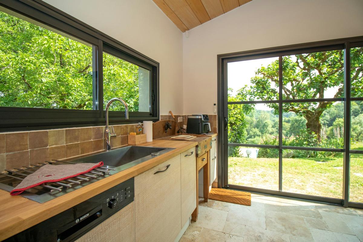 La cuisine, avec des baies vitrées ouvertes sur le jardin