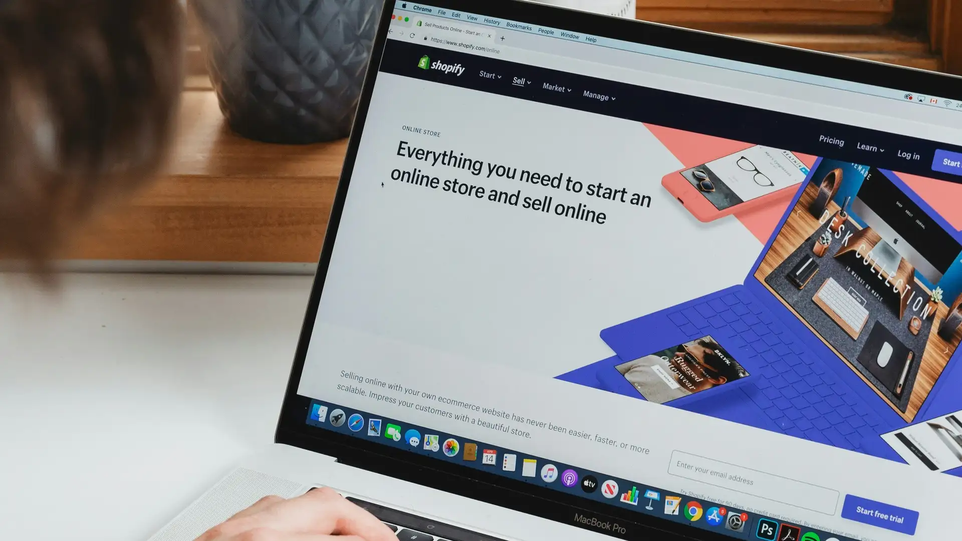 A person is typing on a laptop that says Shopify on the screen.