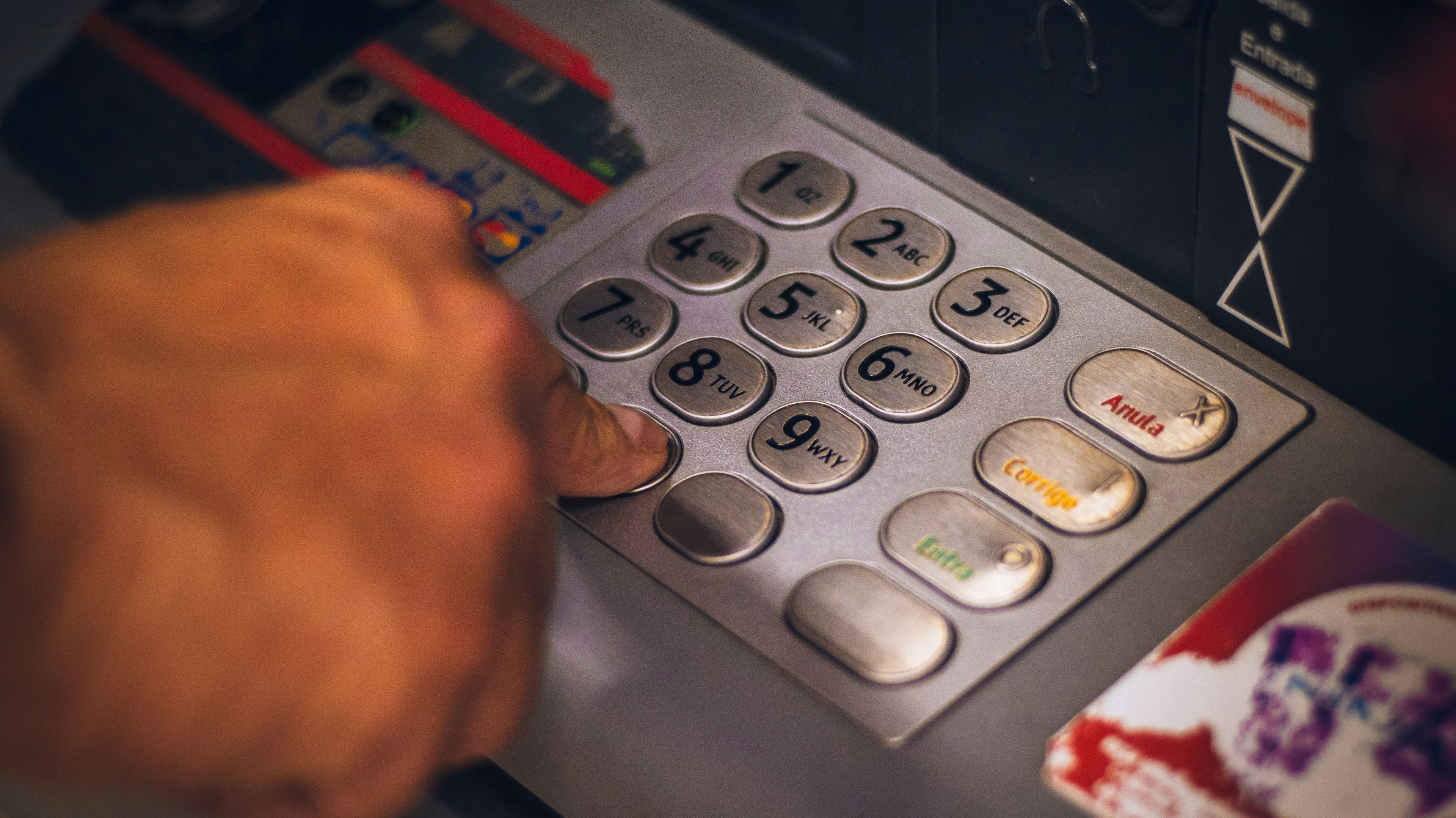 a person is using an atm machine to withdraw money .