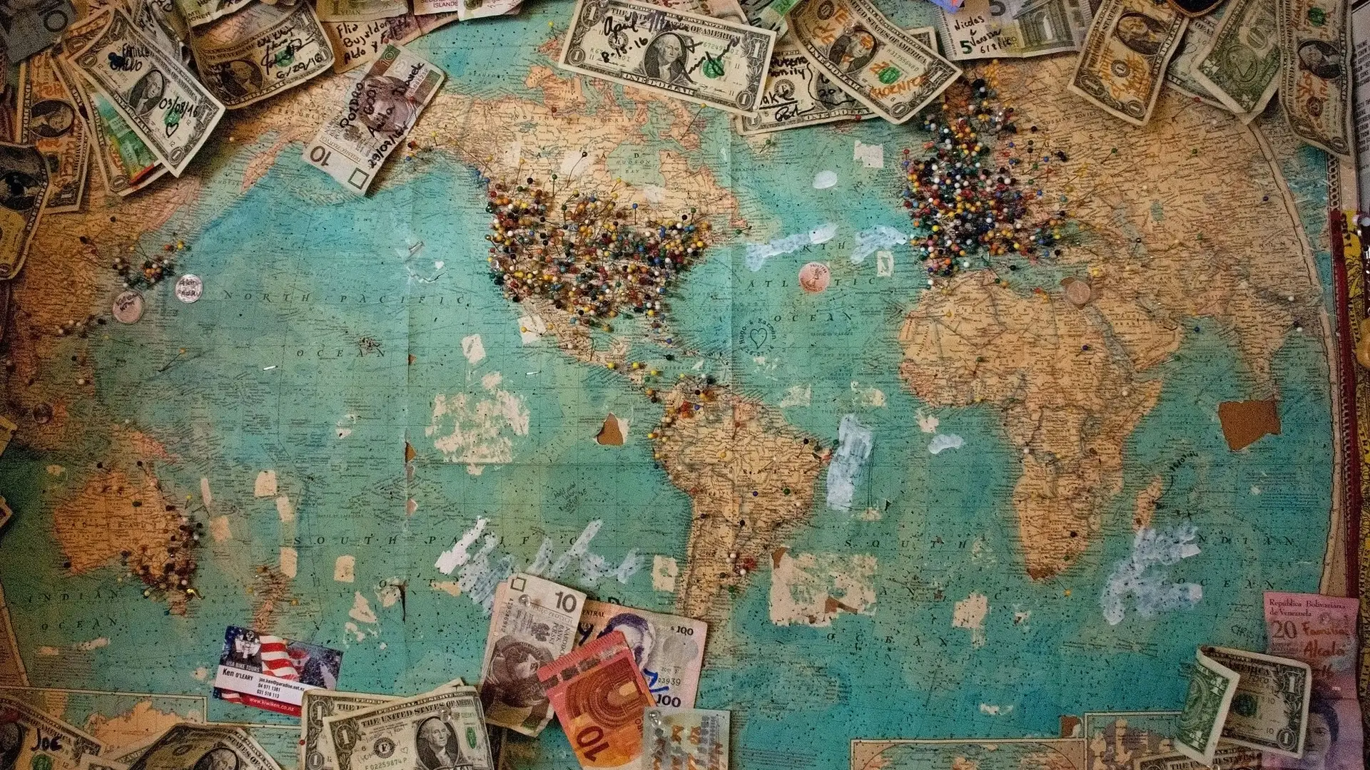 A map of the world covered in money and pins.