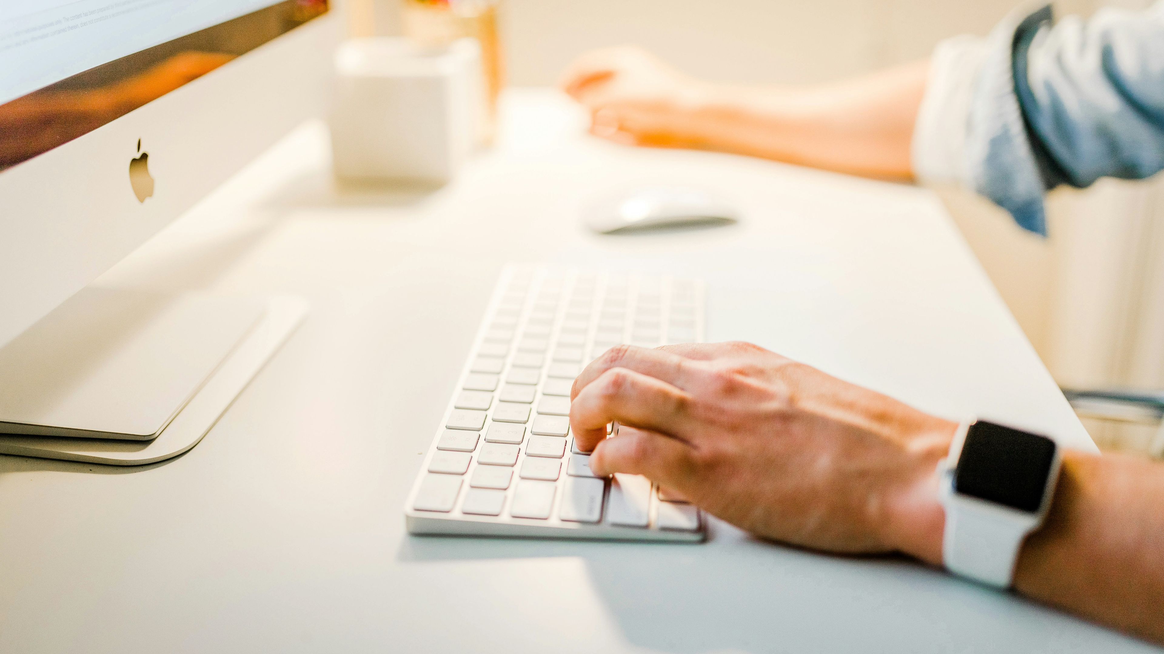a person wearing an apple watch is typing on a computer keyboard .