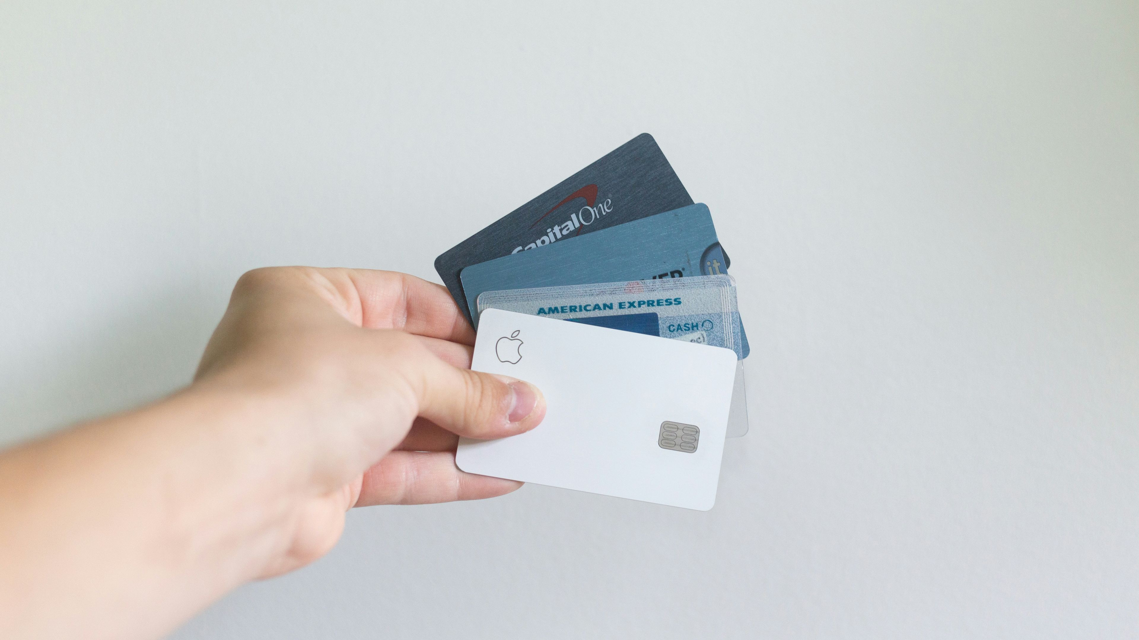 a person is holding three credit cards in their hand .