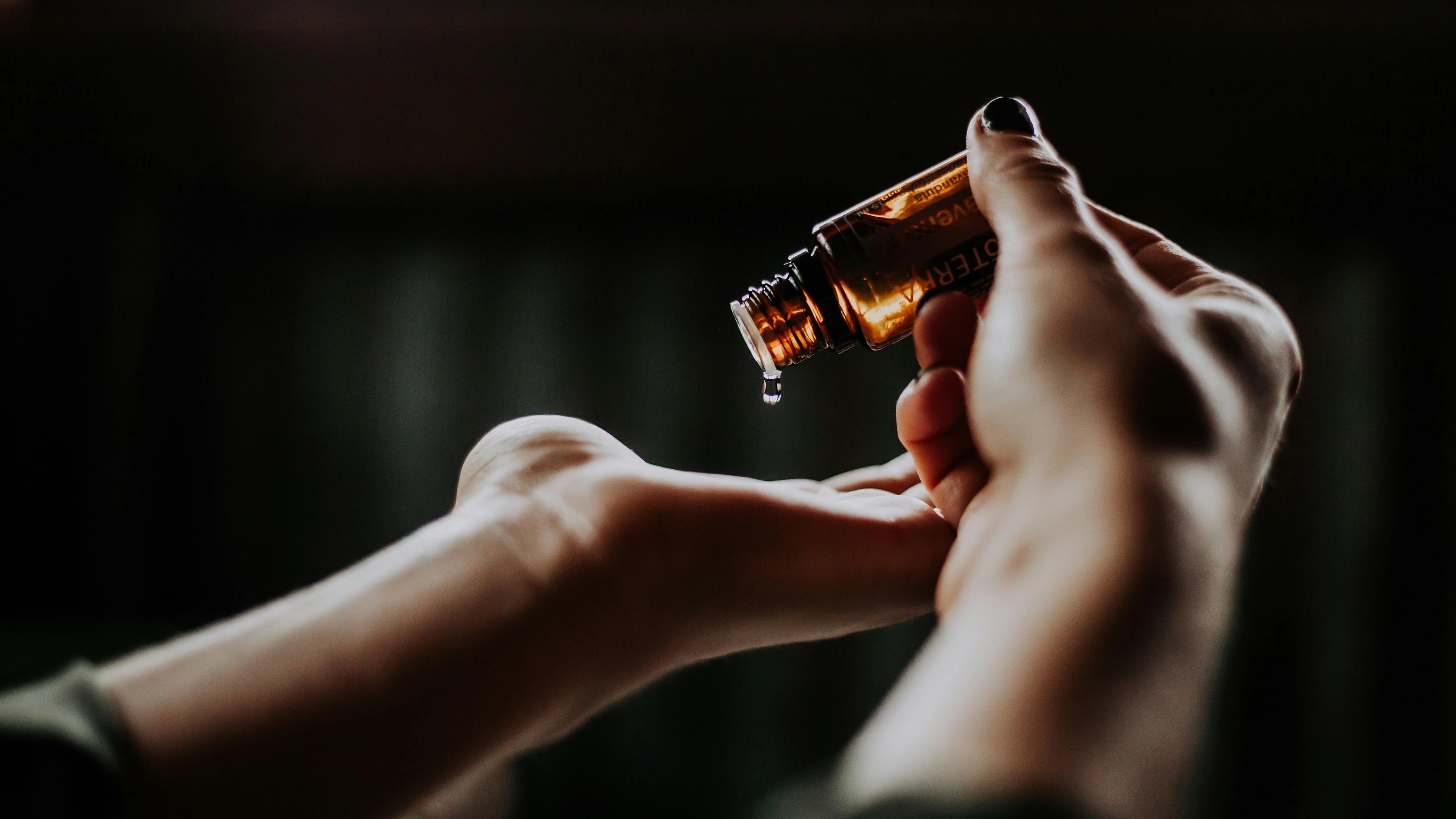 a woman is pouring essential oil into her hand .