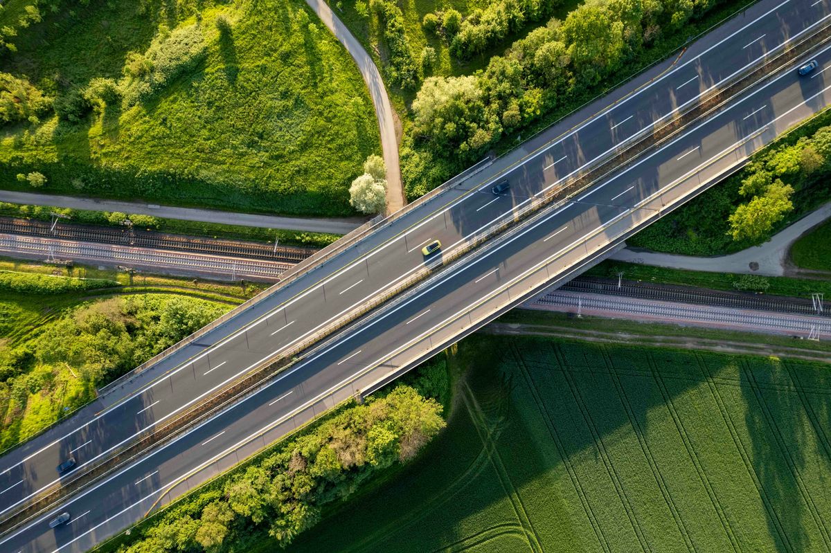Cars driving on road with greenery below.