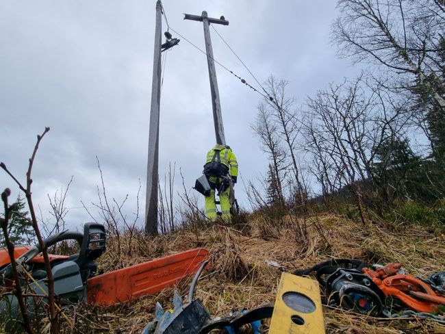 Montør som klatrer i strømstolpe.