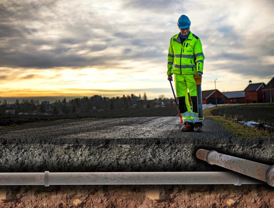 Mann som skal legge et rør under en vei