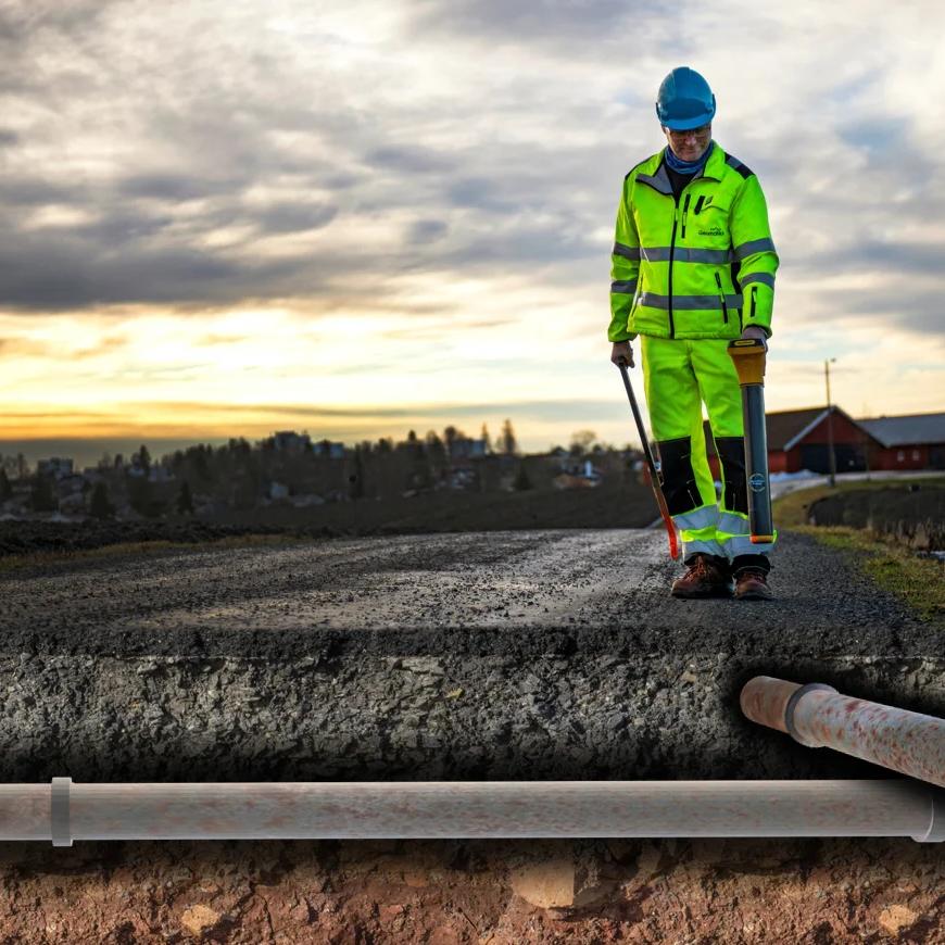 Mann som skal legge et rør under en vei