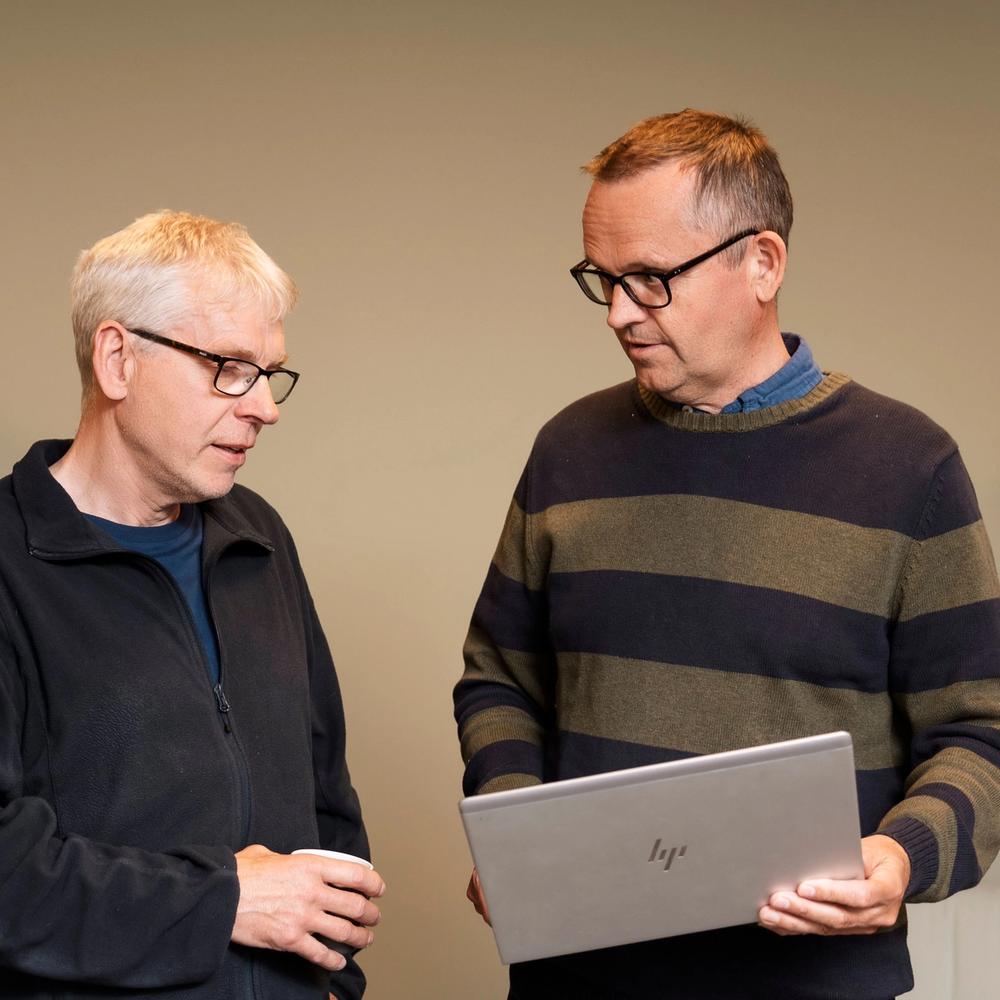 To personer som står å ser på en PC