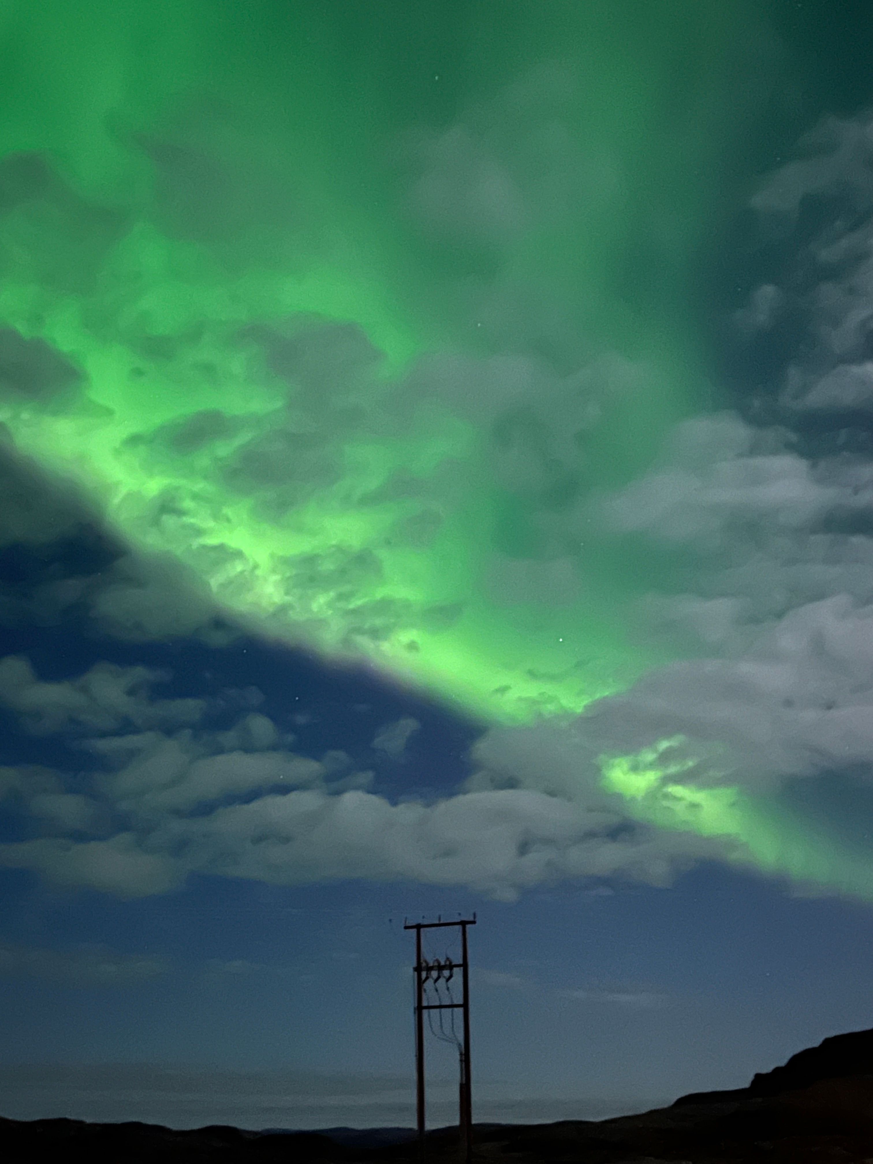 Bilde av en strømmast med nordlys bak