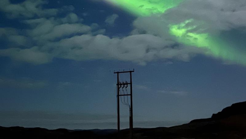Bilde av en strømmast med nordlys bak