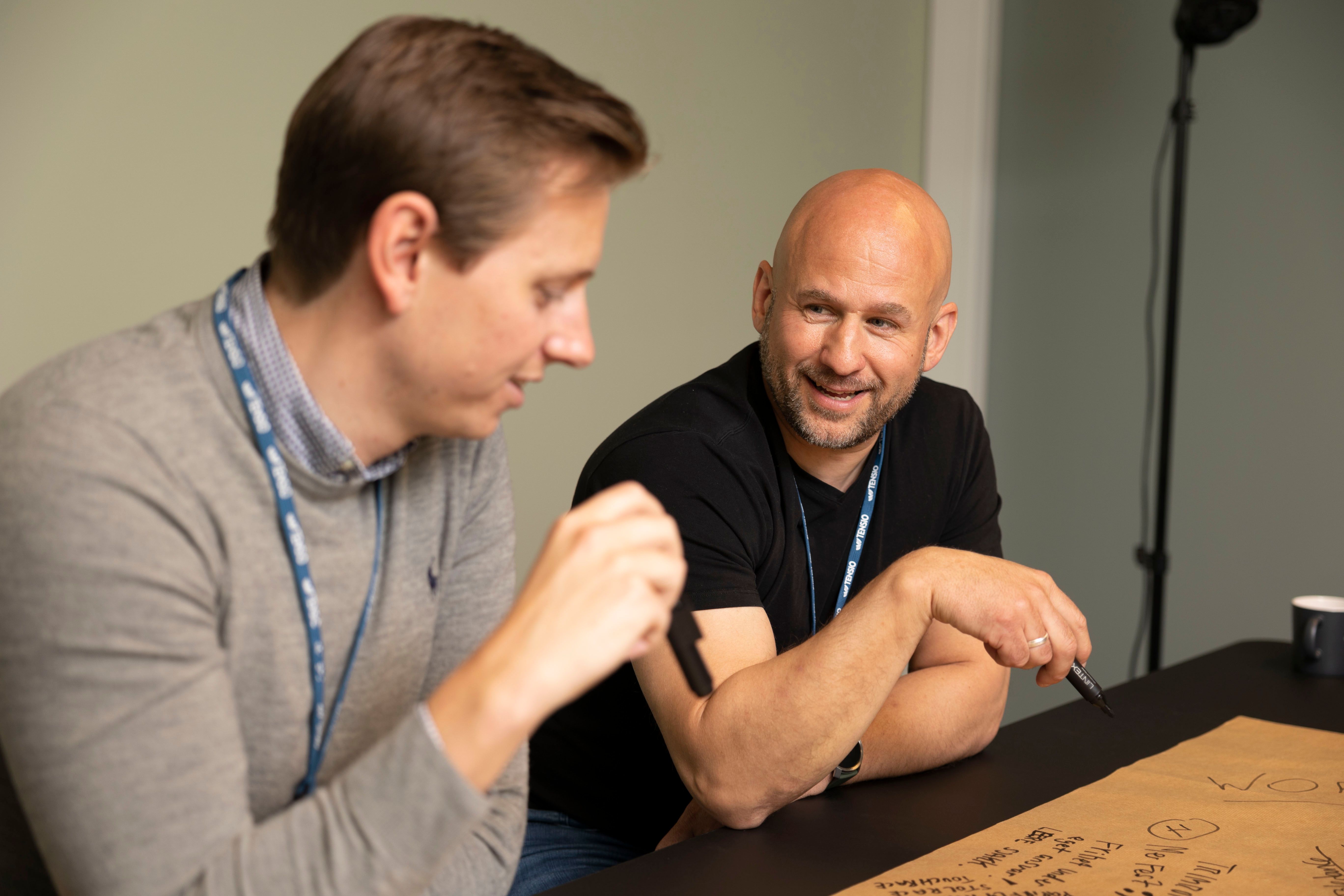 To personer som sitter ved et bord å snakker med hverandre