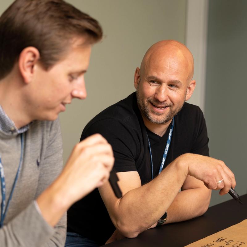 To personer som sitter ved et bord å snakker med hverandre