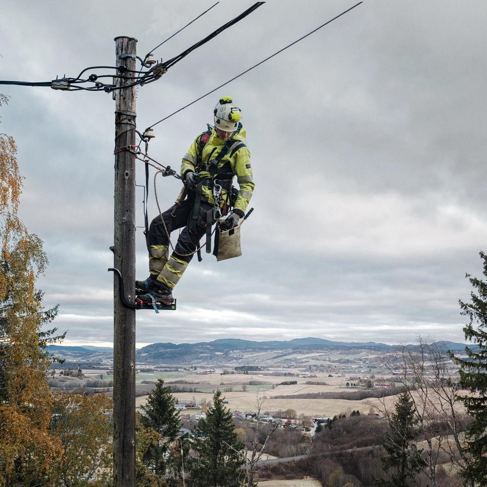 Montør som henger i en strømstolpe