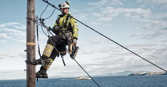 Montør i stolpe, med sjøutsikt