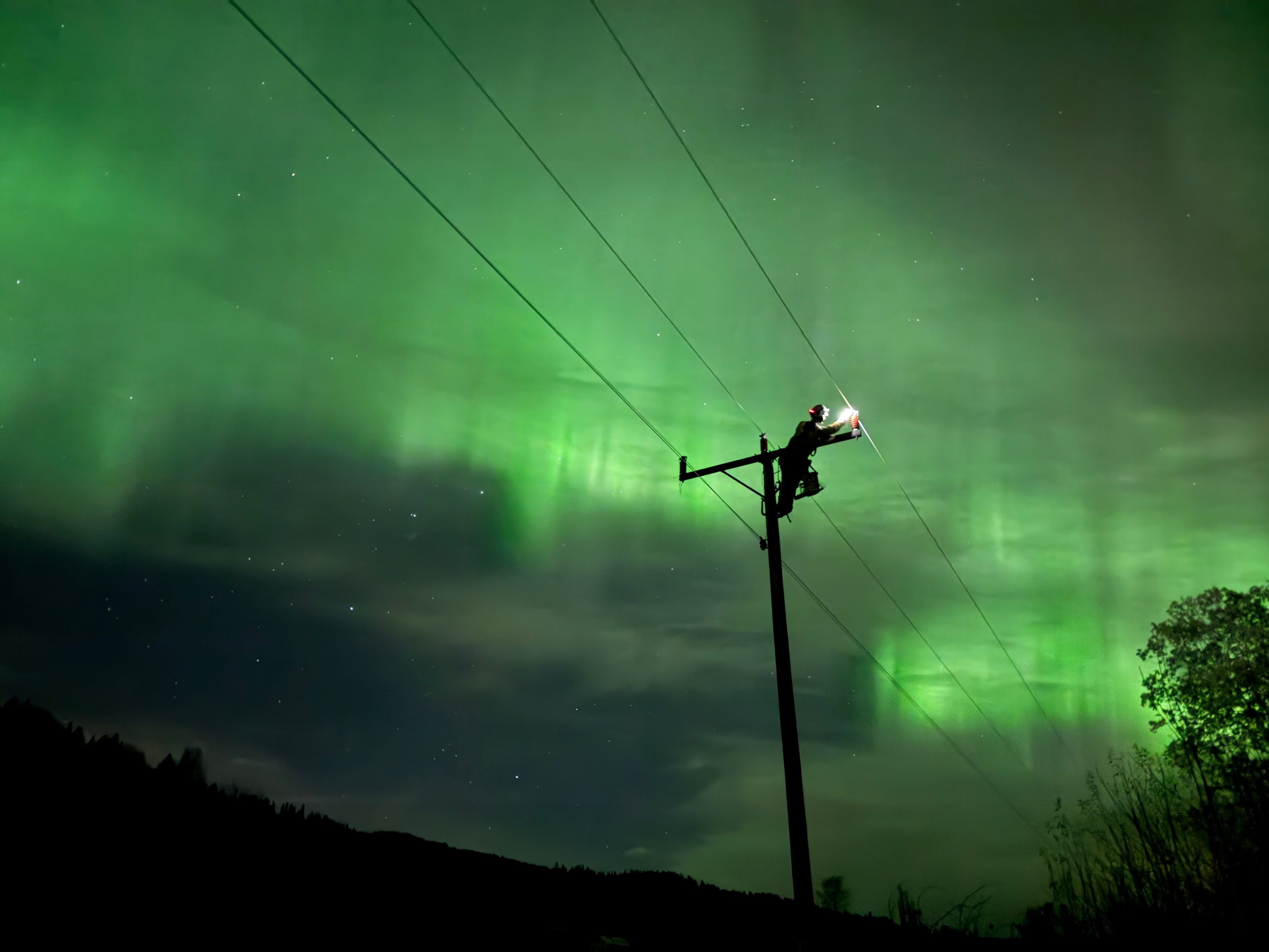 Montør ute på natten i vakkert nordlys for å fikse feil i strømnettet