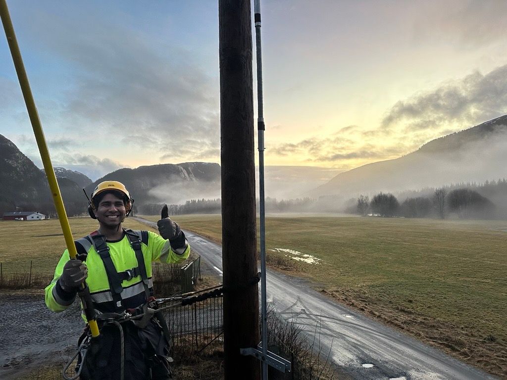Bilde av en Tensio-montør som klatrer i en strømstolpe
