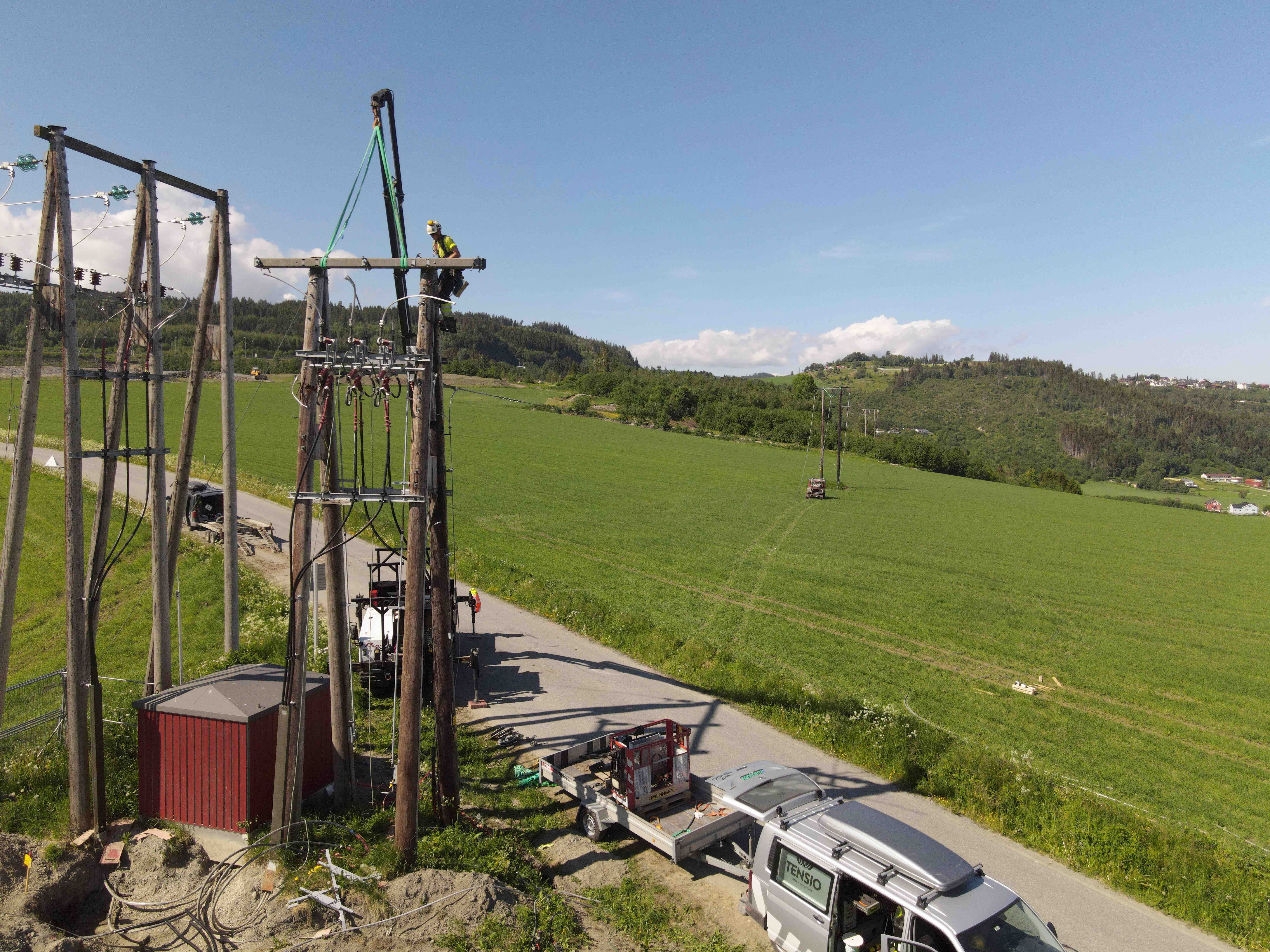 Tensio-montør som klatrer i en høyspentstolpe