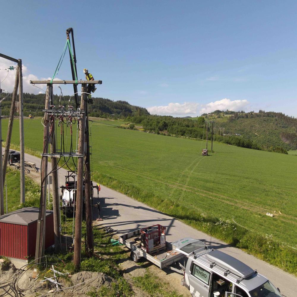Tensio-montør som klatrer i en høyspentstolpe
