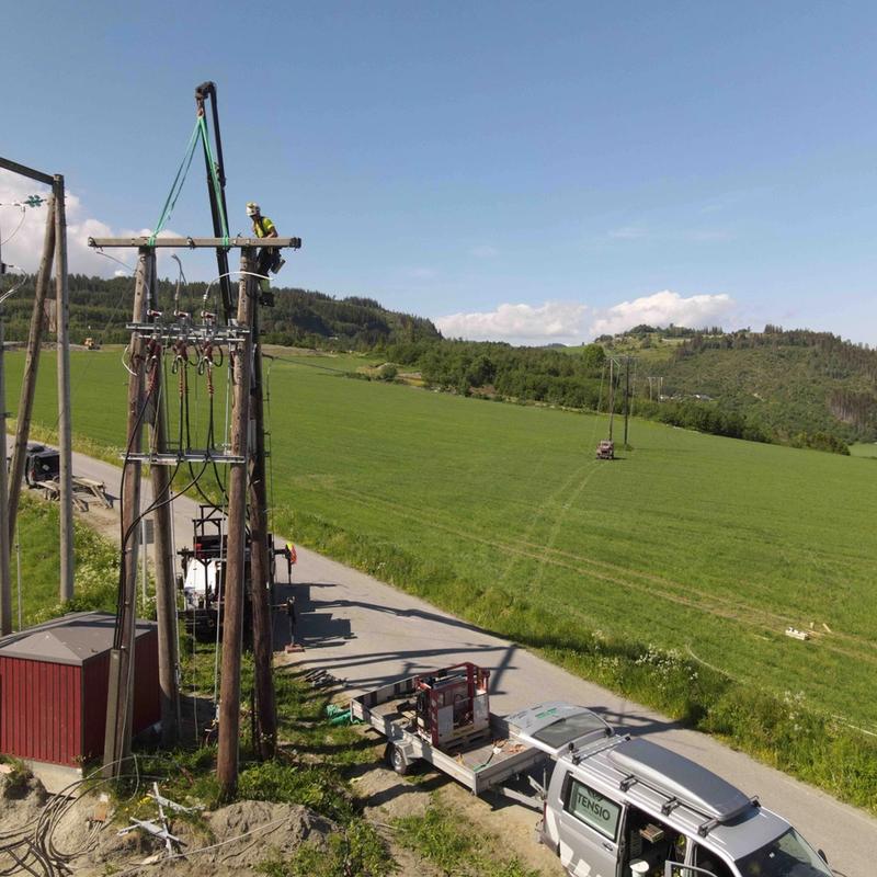 Tensio-montør som klatrer i en høyspentstolpe