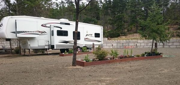 A fifth-wheel RV parked at Duneaway Park with trees and greenery in the foreground.