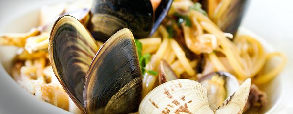 A bowl of linguine with steamed clams and mussels in their shells.
