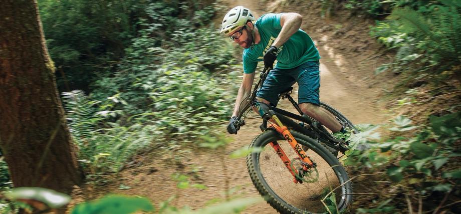 A mountain biker leans into a turn on a forested dirt trail at Whiskey Run Mountain Biking Trails on the Southern Oregon Coast.