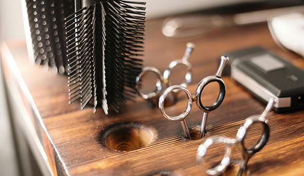 Close-up of barber tools, including scissors and combs, arranged on a wooden workstation.
