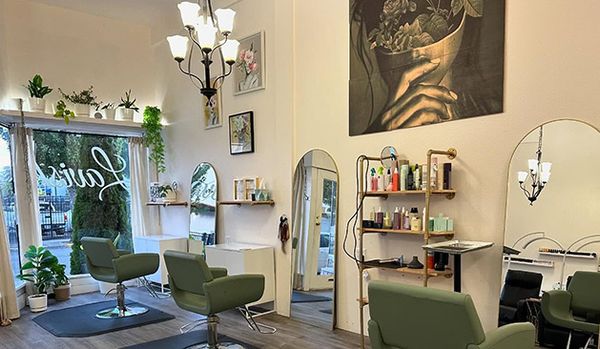 Interior image of hair salon with three stylist chairs, mirrors and hair products.
