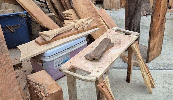 A collection of assorted wooden planks, blocks, and carved pieces, including a small wooden stool or table.