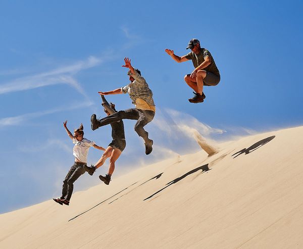Four people leap off a steep sand dune in mid-air against a blue sky at Oregon Dunes National Recreation Area."  Informative — captures the action and energy of the moment.  4. Man walking up a dune leaving footprints  alt="A man with a backpack walks up a large sand dune, leaving a trail of footprints behind him, with evergreen trees in the distance at Oregon Dunes National Recreation Area."  Informative — describes the figure, the footprint trail, and setting.  Summary: 4 images, all classified as informative, all under 125 characters, none require a long description.